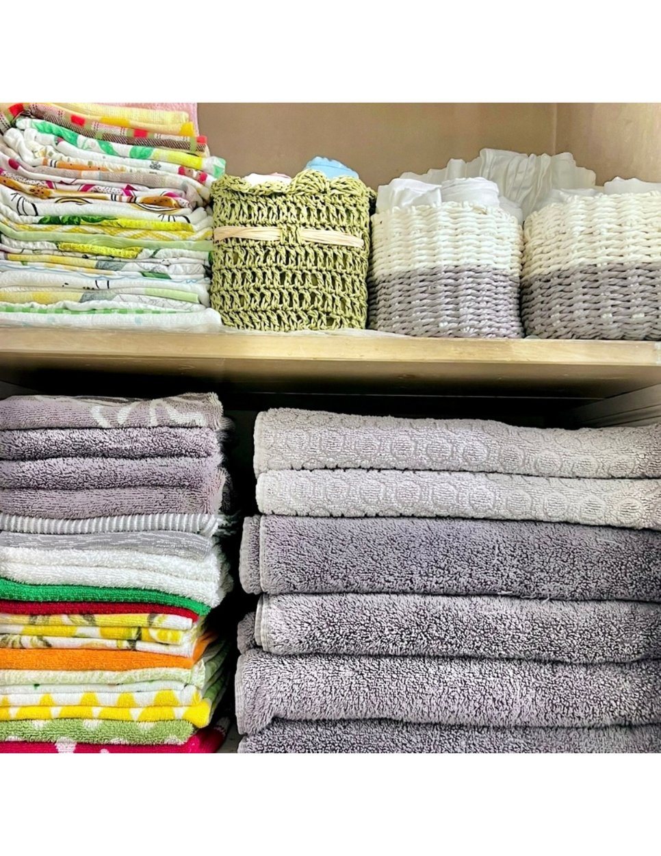 Organized linen closet with folded towels, blankets, and storage baskets