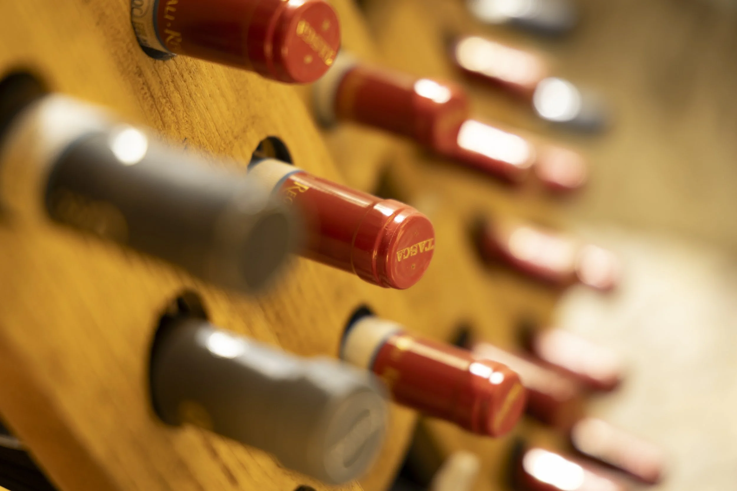 Close-up of hot glue sticks arranged in a wooden holder, with some sticks light gray and others red.