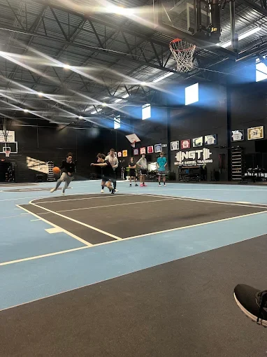 People playing basketball on an indoor court with a black ceiling and banners on the wall.