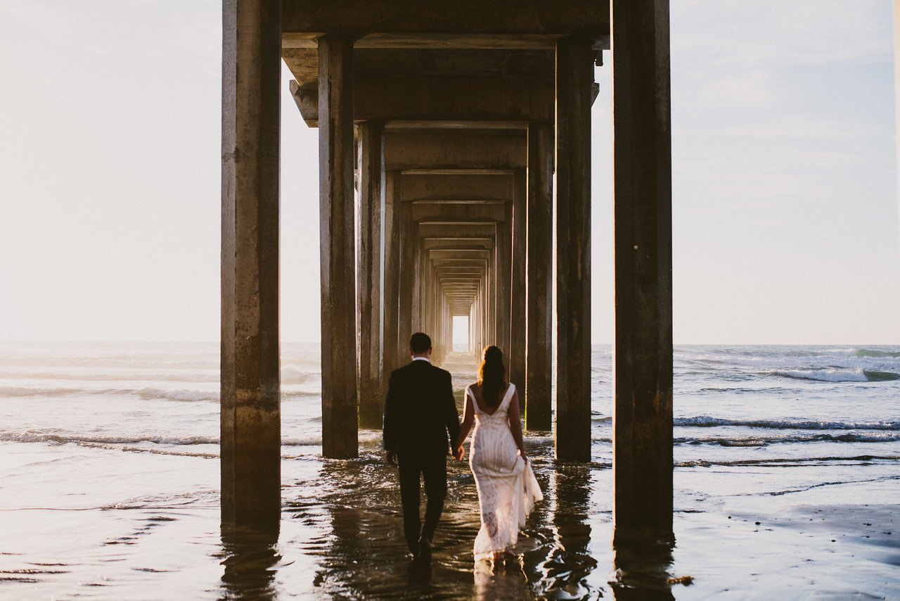 Bride and Groom walk under La Jolla Pier- Destination Fine Art Wedding Photographer
