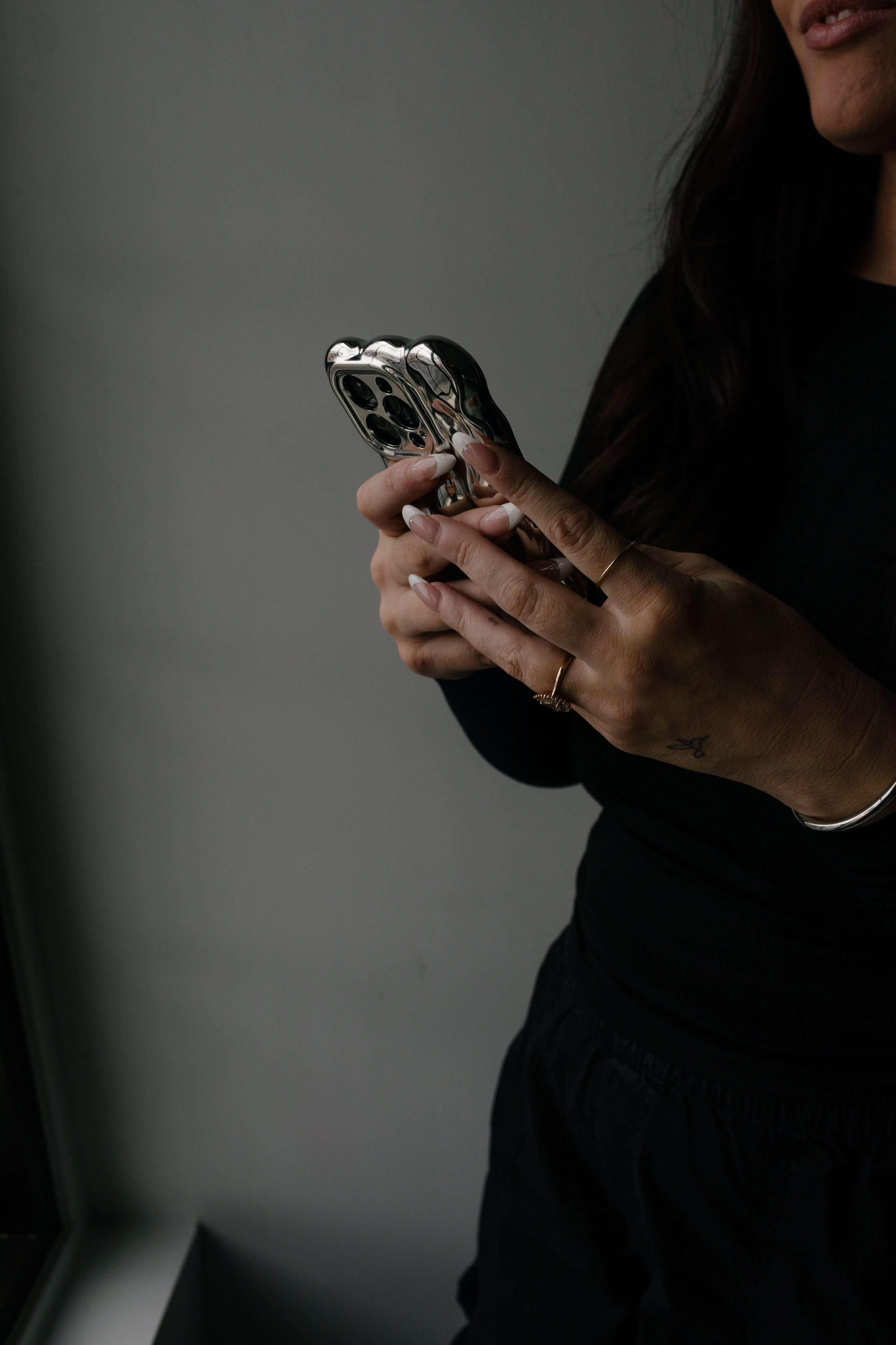 Woman in all black outfit holding a silver phone
