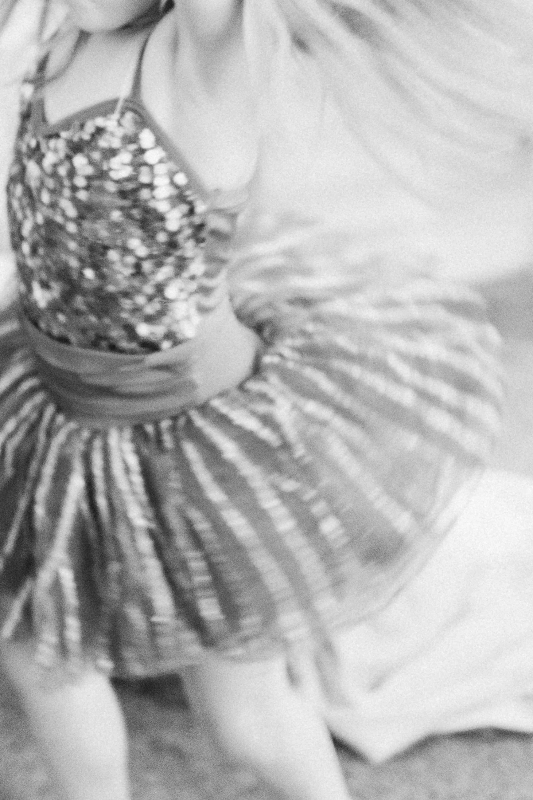 Close-up of a young girl wearing a dress with sequins, sitting on a floor.