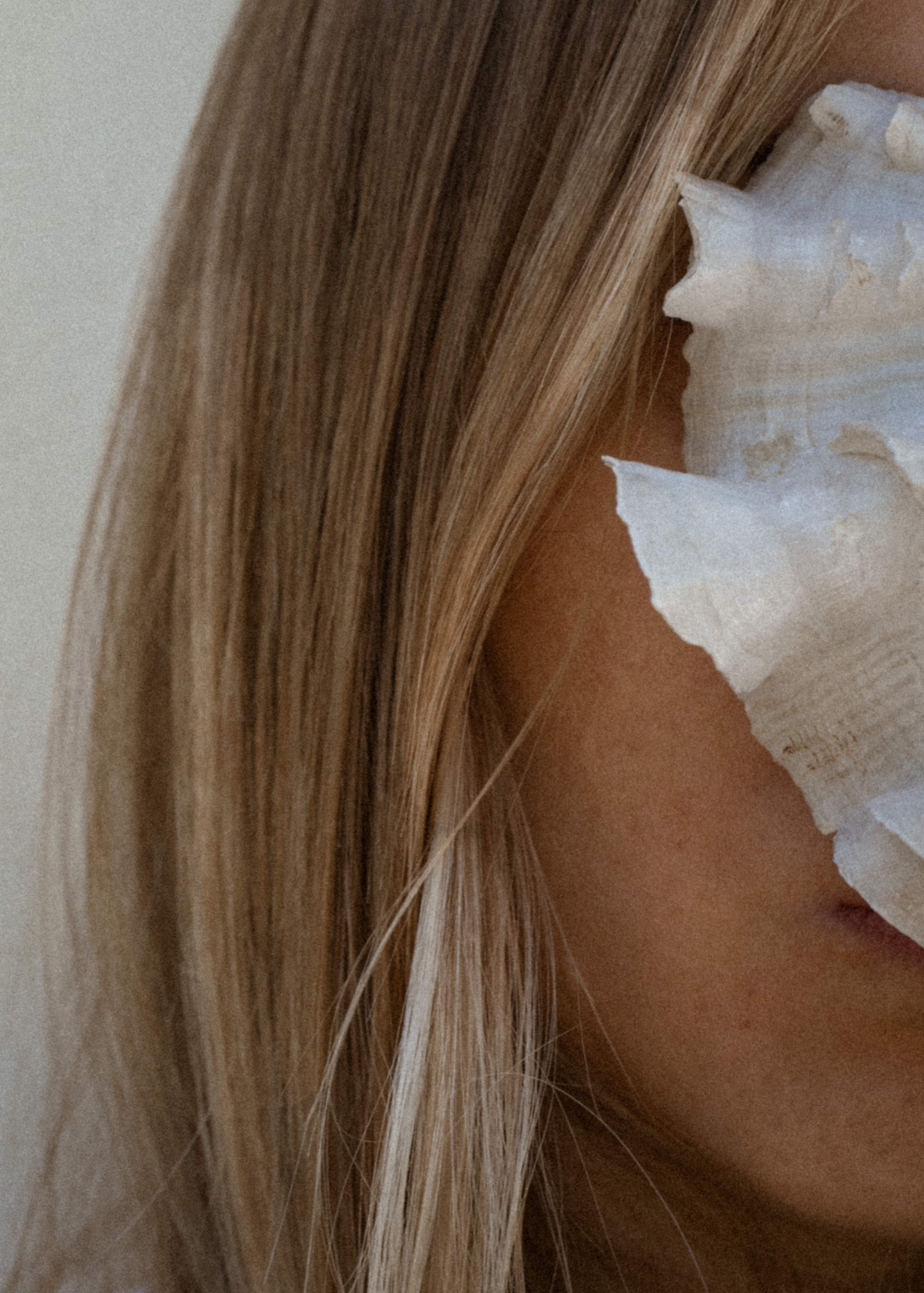 Close-up of a woman's face with blonde hair and a tissue covering her nose.