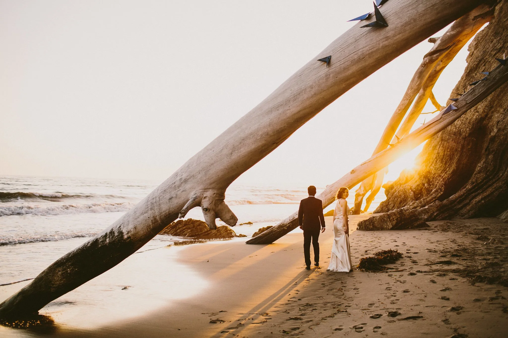Bride and Groom walking together on a beach in Santa Barbara, bride looks back- Destination Fine Art Wedding Photographer