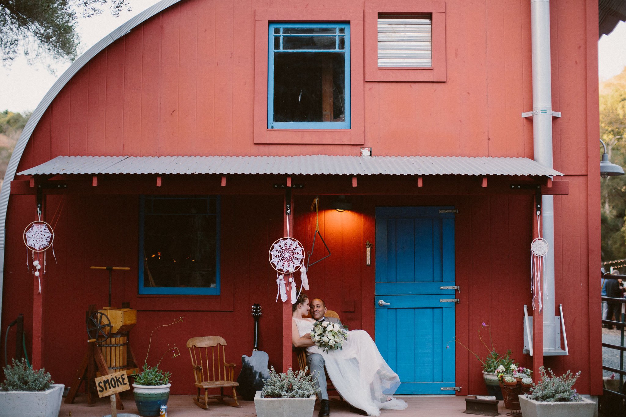 bride and groom sitting in front of wedding cabin