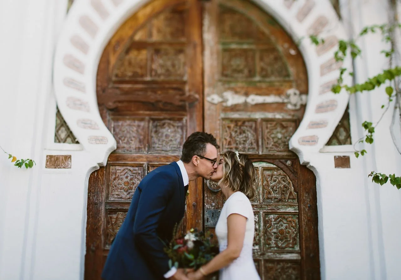 Bride and Groom kiss in front of door at korakia Pensione in Palm Springs- Fine Art Wedding Photographer