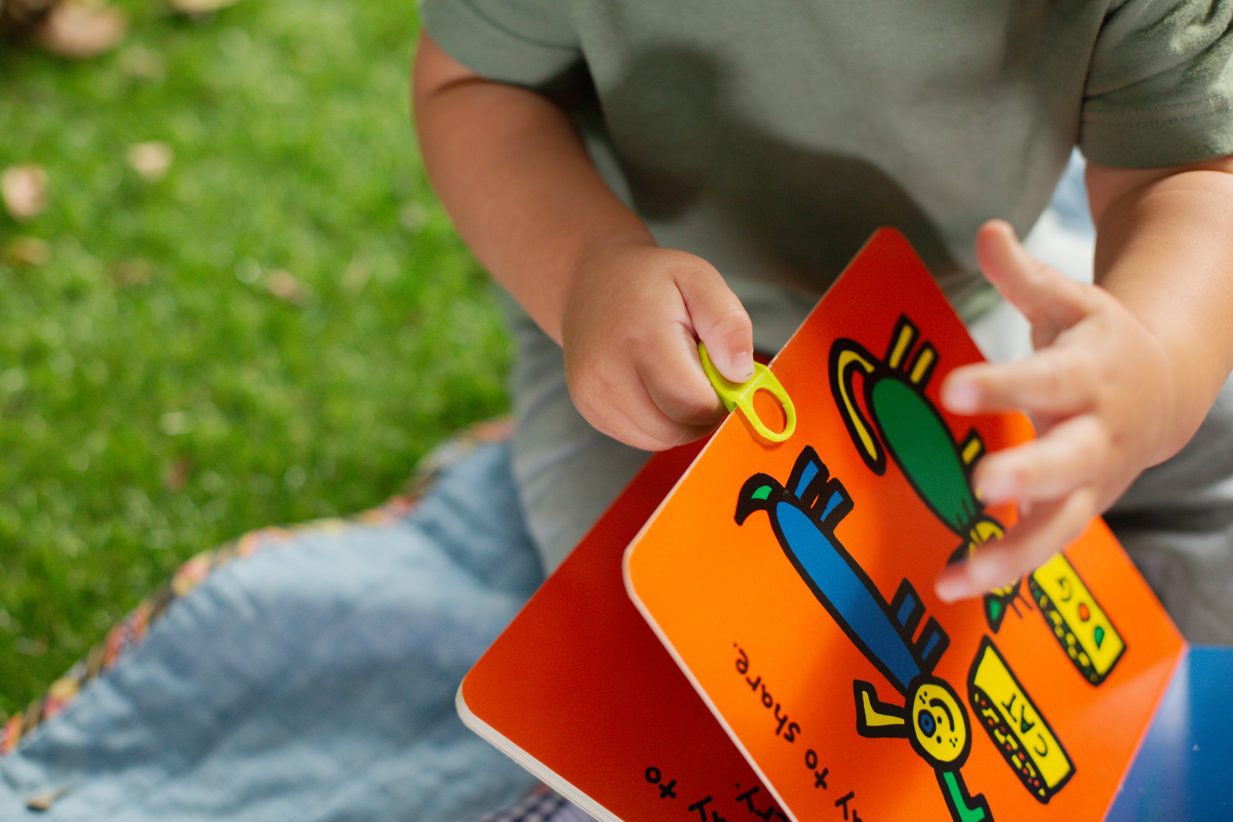 Close-up of a child using Flipps page turning tools to read board book.