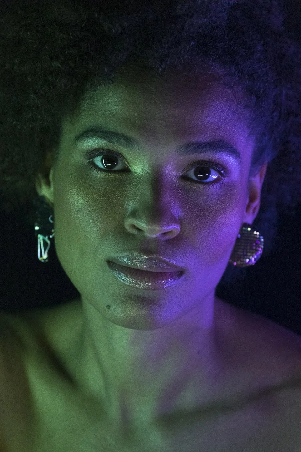 Nahaufnahme eines schwarzen Frauenporträts mit Color- und Neon-Lichteffekten, glänzenden Lippen und großen Ohrringen.