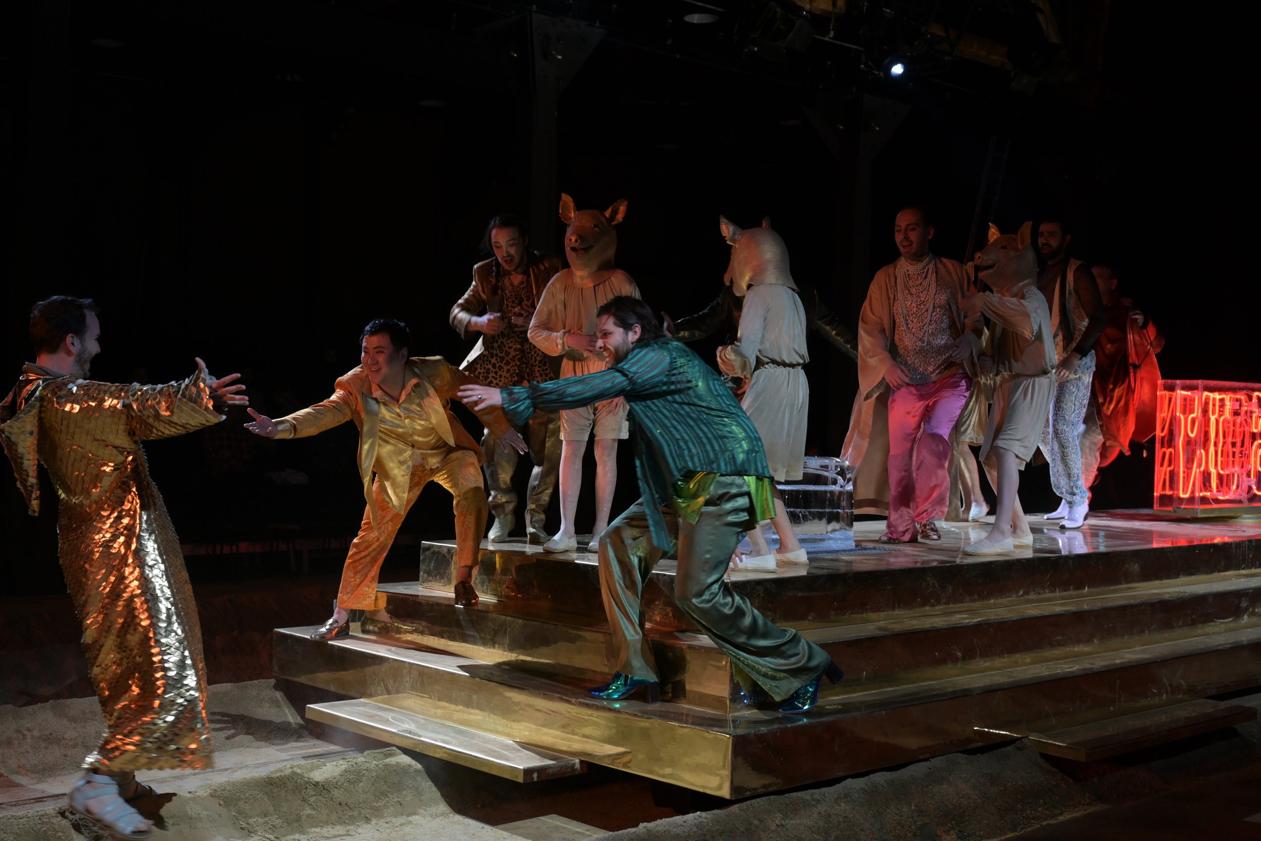 Menschen auf einer Bühne, die in Tierkostümen und bunten Kleidung spielen und tanzen.
