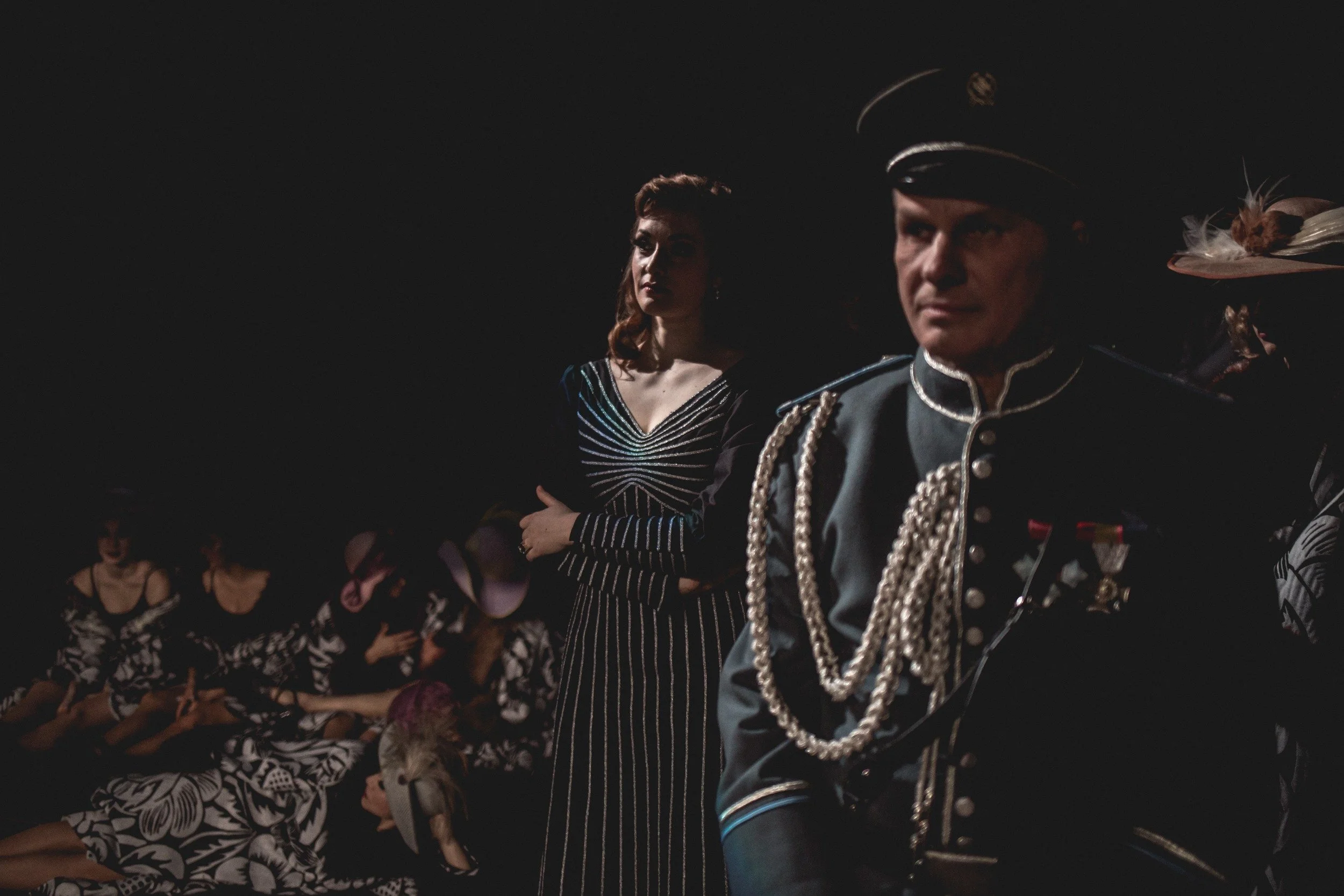 Szene mit Menschen in historischer Kleidung, dunkler Hintergrund, dramatische Beleuchtung.