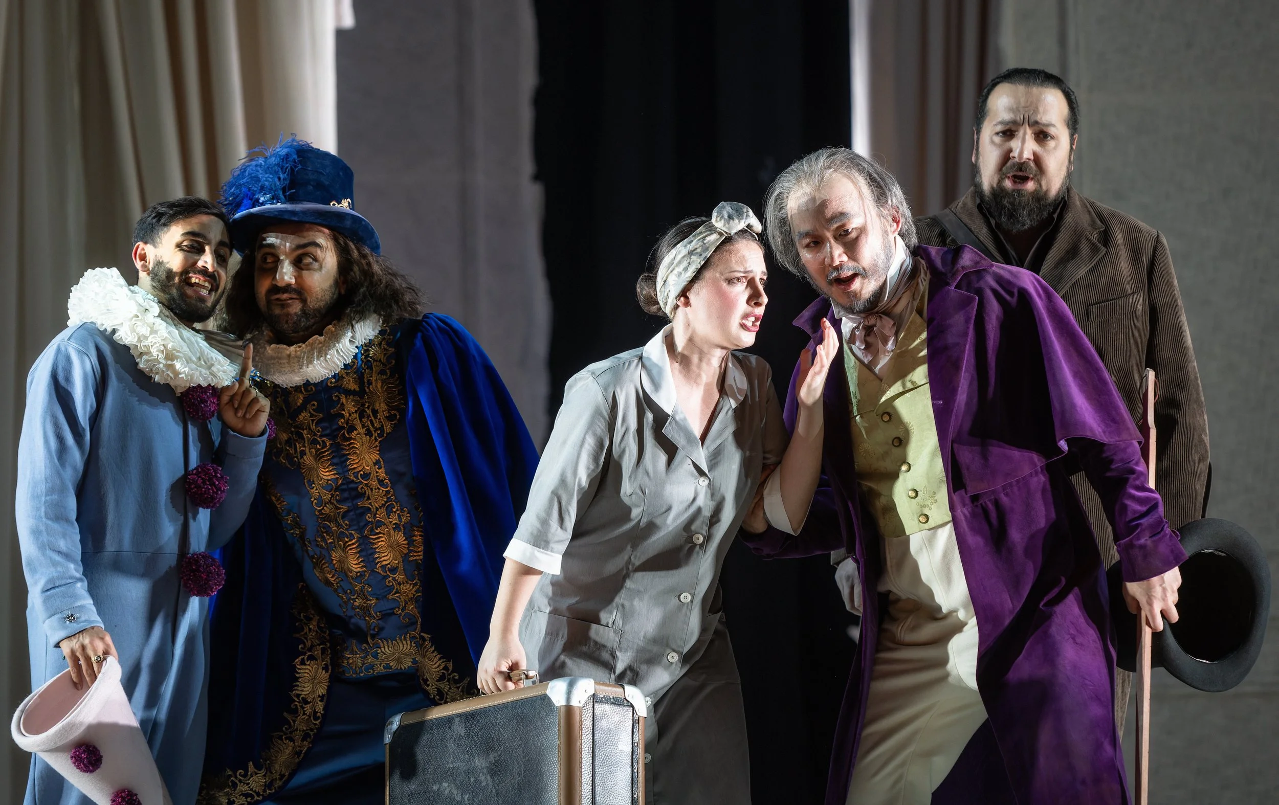 Theaterensemble in period costumes auf der Bühne, dargestellt in einer Szene, die emotionale Interaktion zeigt.