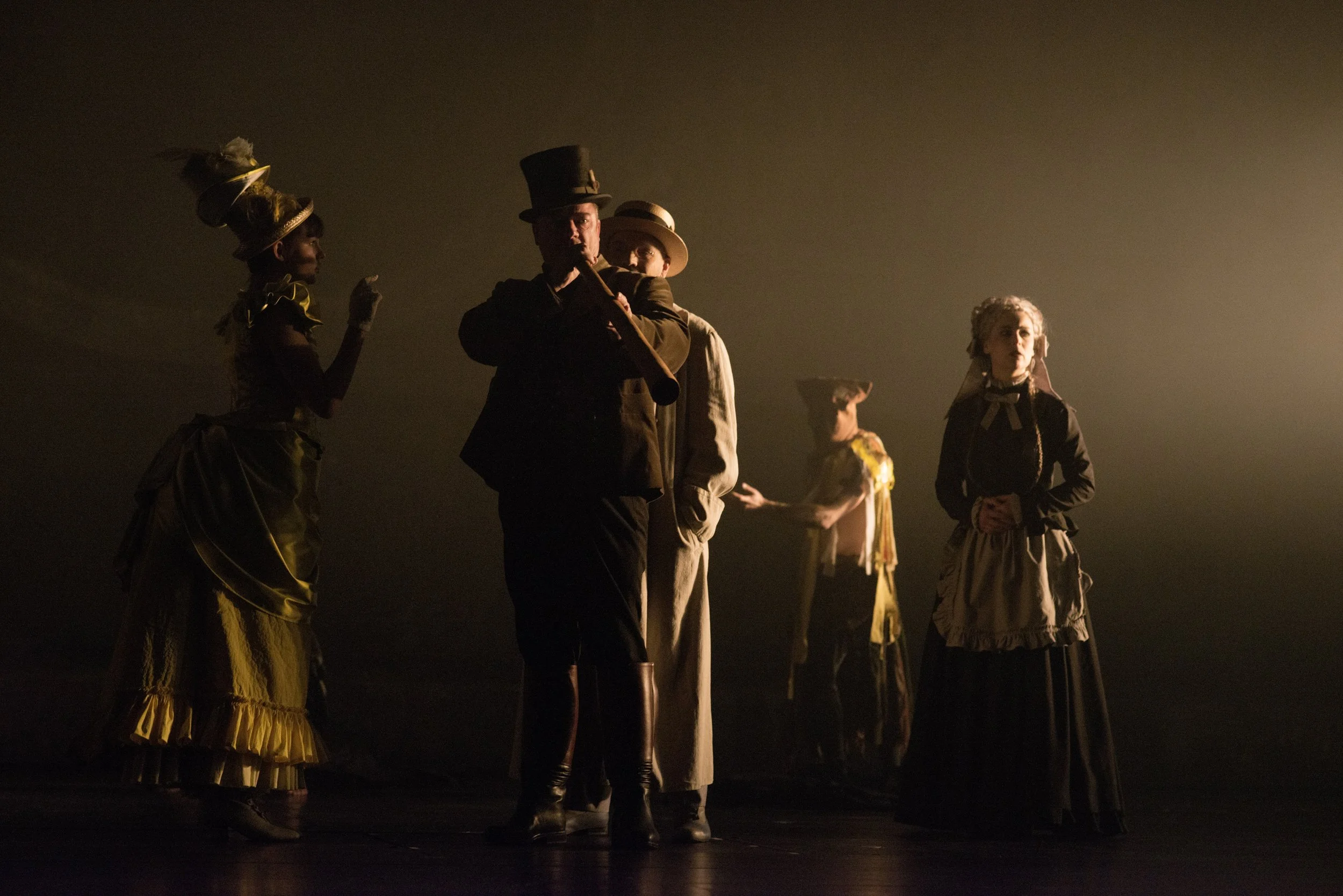 Fünf Personen in historischen Kostümen auf einer Bühne bei einem Theaterstück, im pietätvollen Licht.