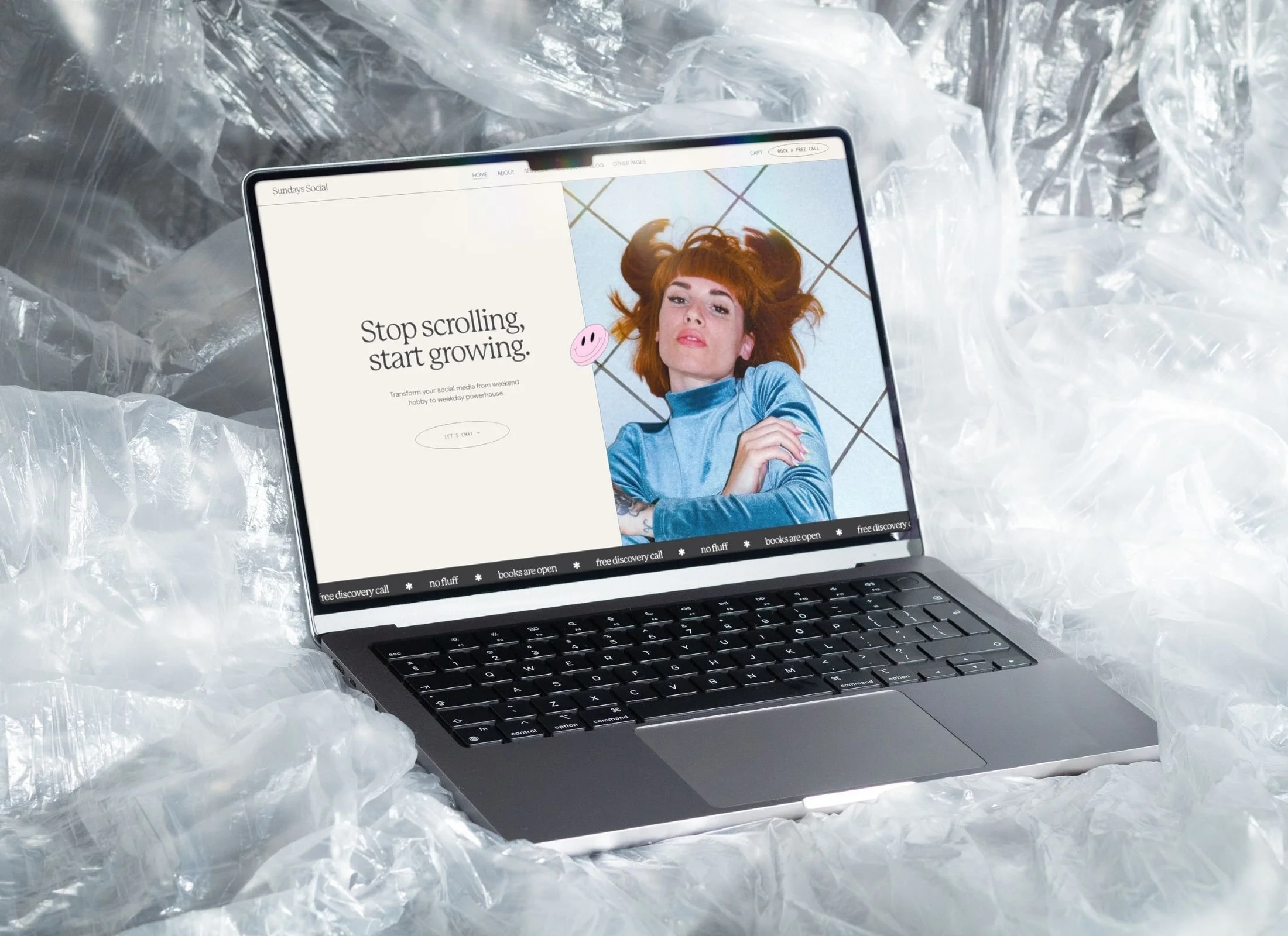 Laptop on crumpled plastic sheet displaying a webpage with a woman with red hair lying on her back, wearing a blue top, with the text 'Stop scrolling, start growing.'