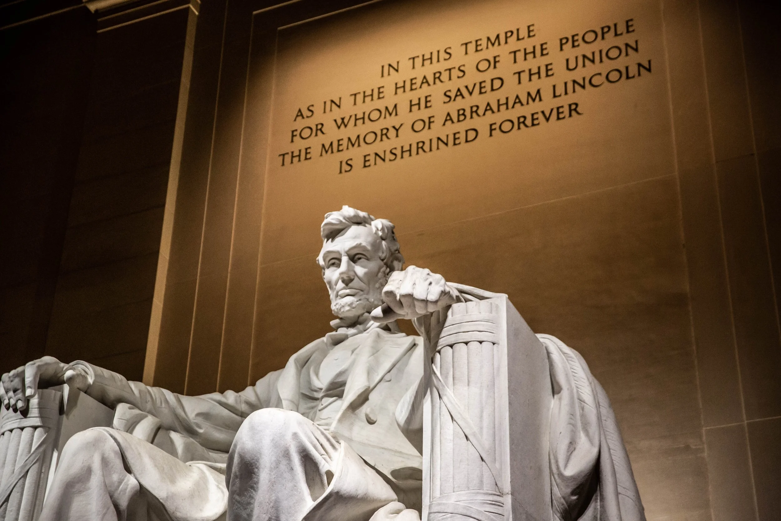 Statue of Abraham Lincoln in front of a wall with an inscription about his contributions.