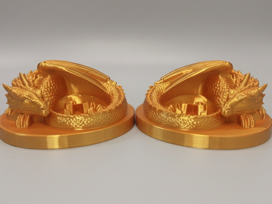 Two identical gold-colored dragon figurines on oval bases, curled with detailed scales and dragon heads resting on their bodies.