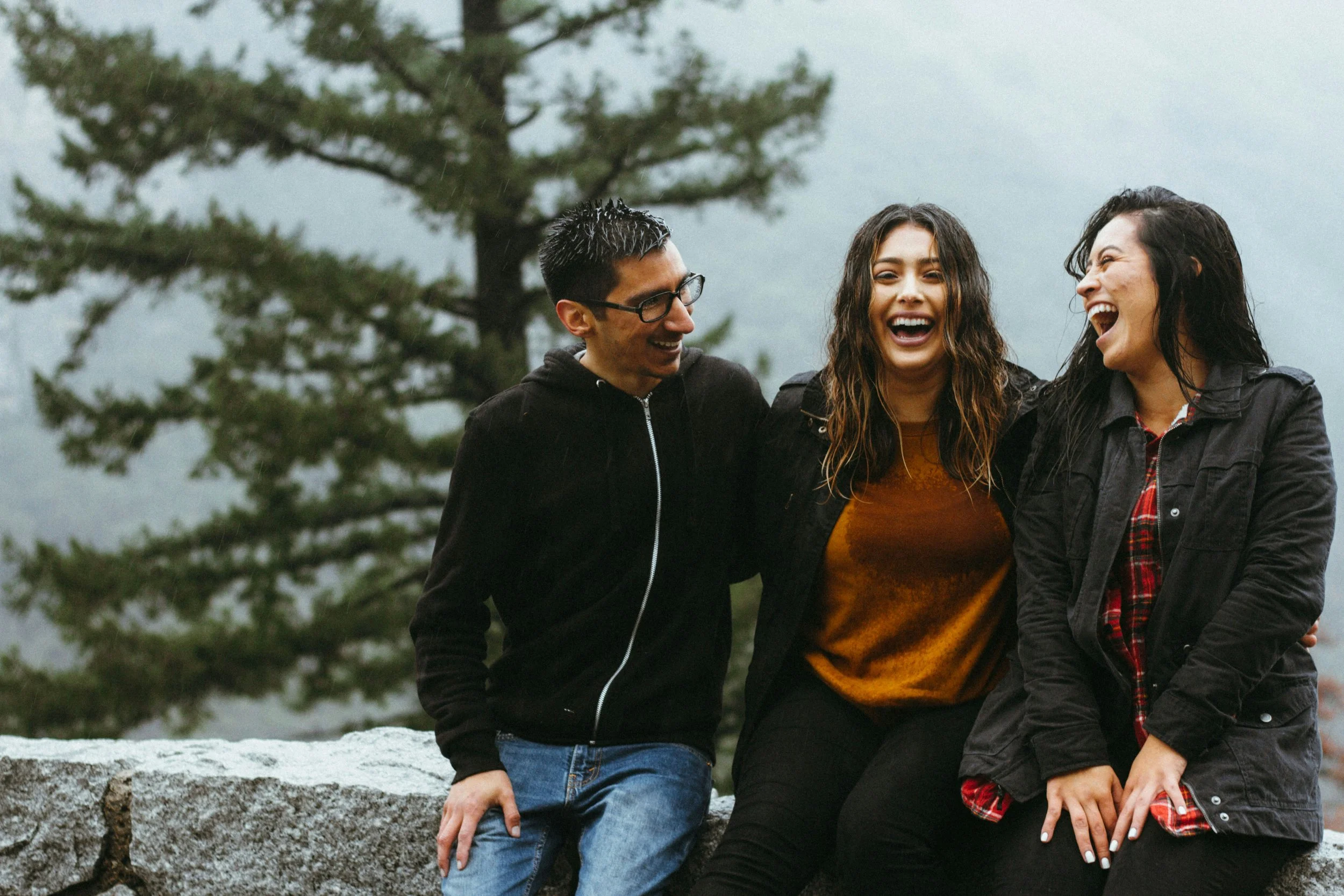 Three polycule partners smiling together, representing connection, trust, and healthy ethical non-monogamous relationships.