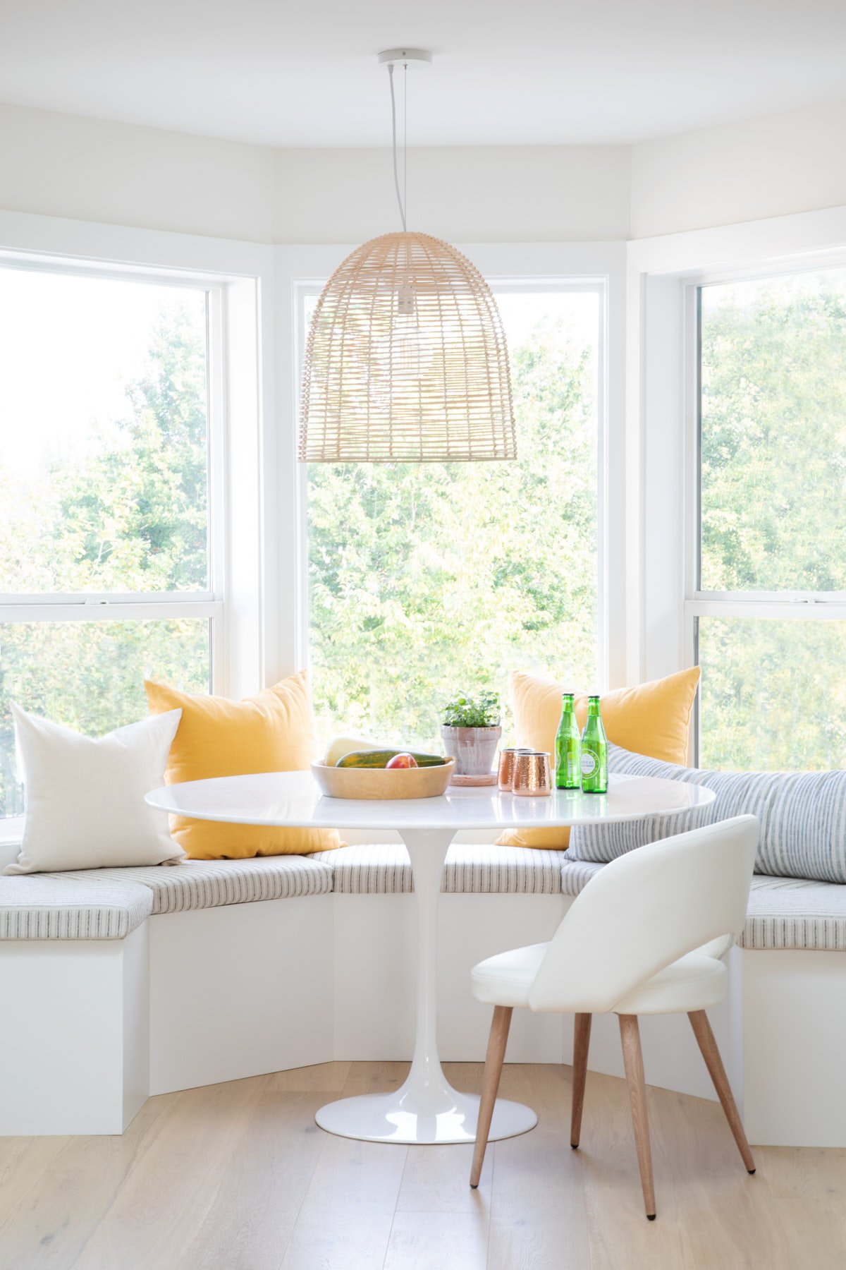 Photo of banket seating, with pillows, a round marble table and white bar stool.