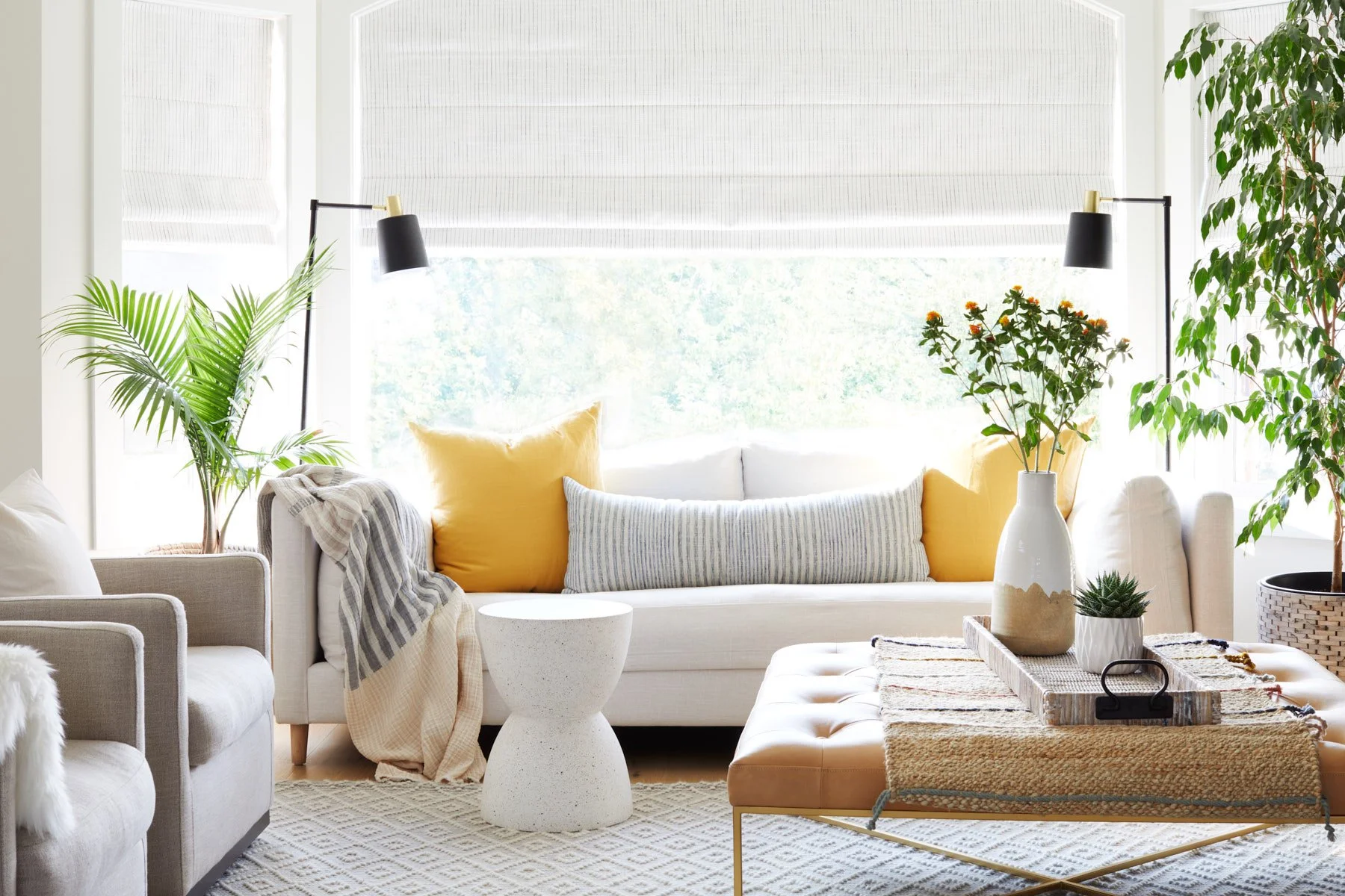 Photo of sofa with leather ottoman in front, tray on ottoman with decor on tray.