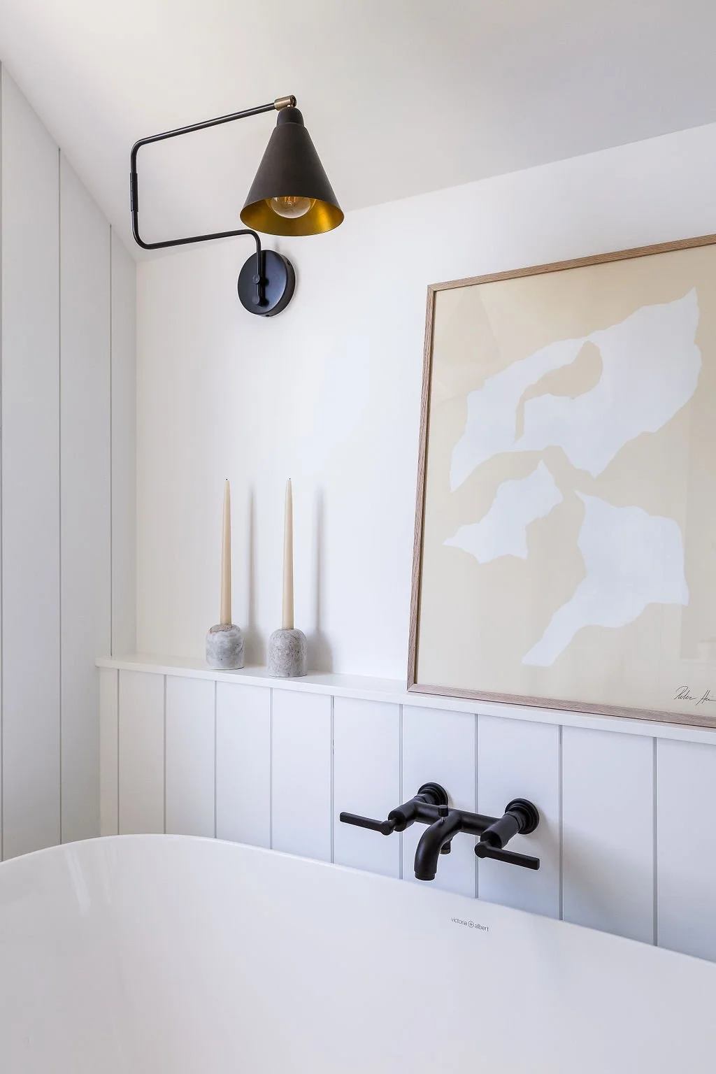 Soaker tub next to window surrounded by art and decor.