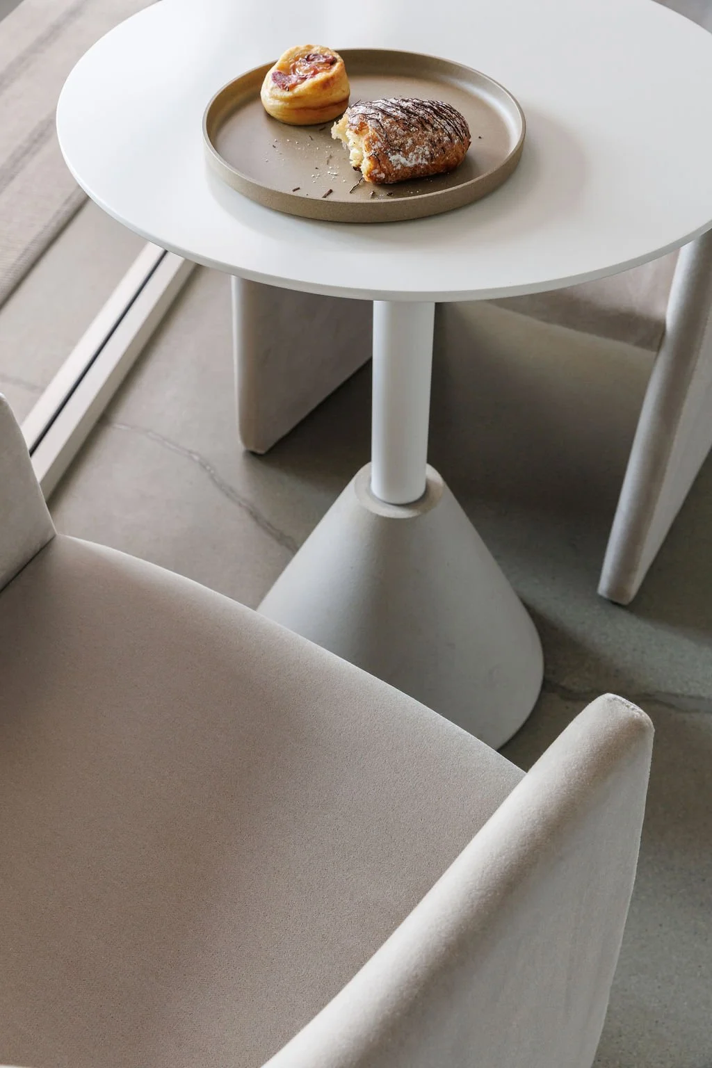 Close-up of bistro table and chairs with pastries on plate. 