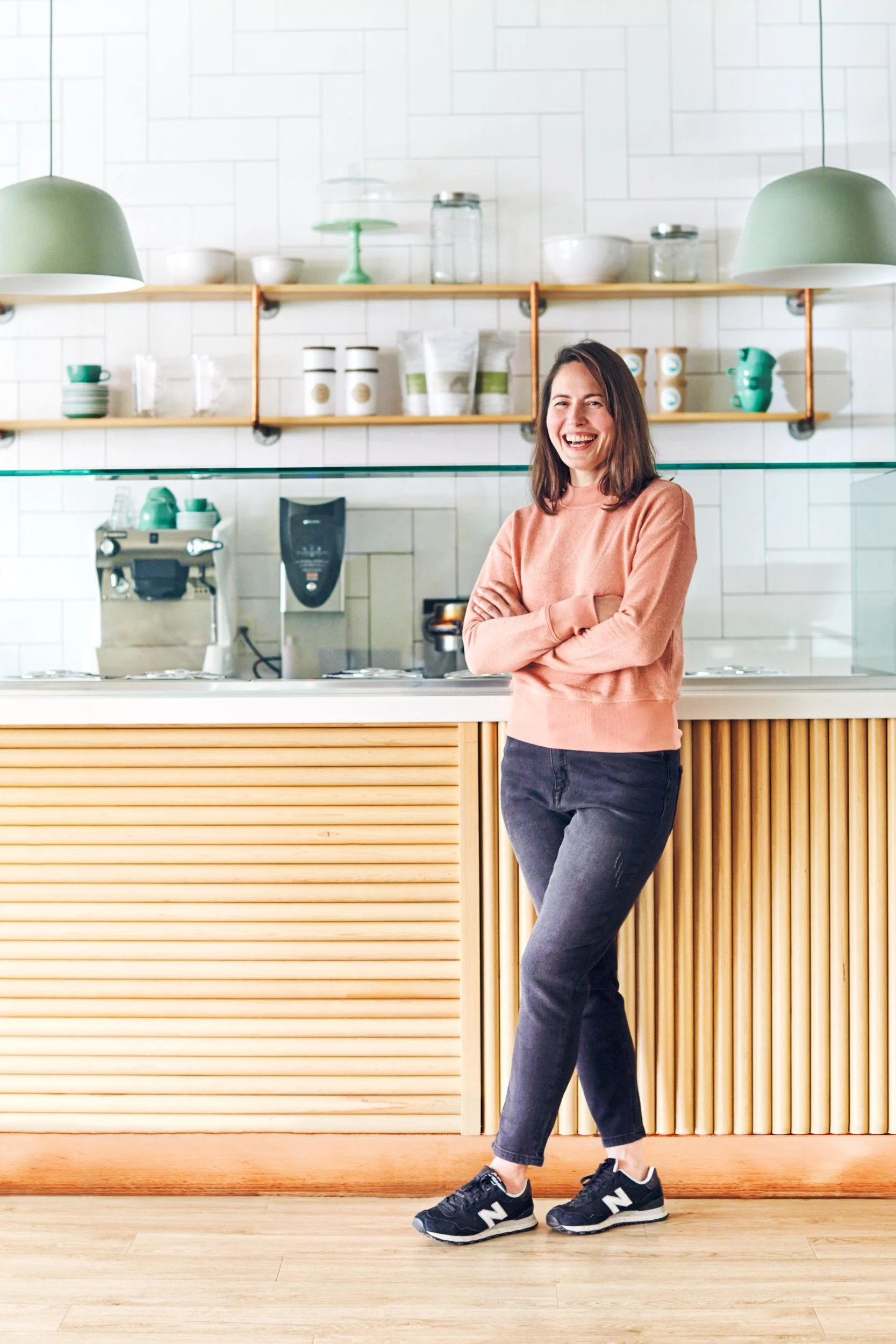 Owner of gelato shop leaning against service counter looking happy.