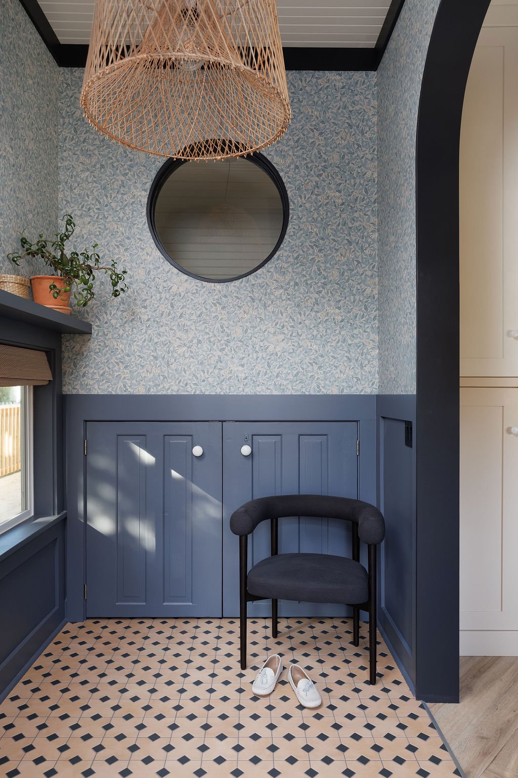 Livley entry with floral wallpaper comfortable side chair and round window.
