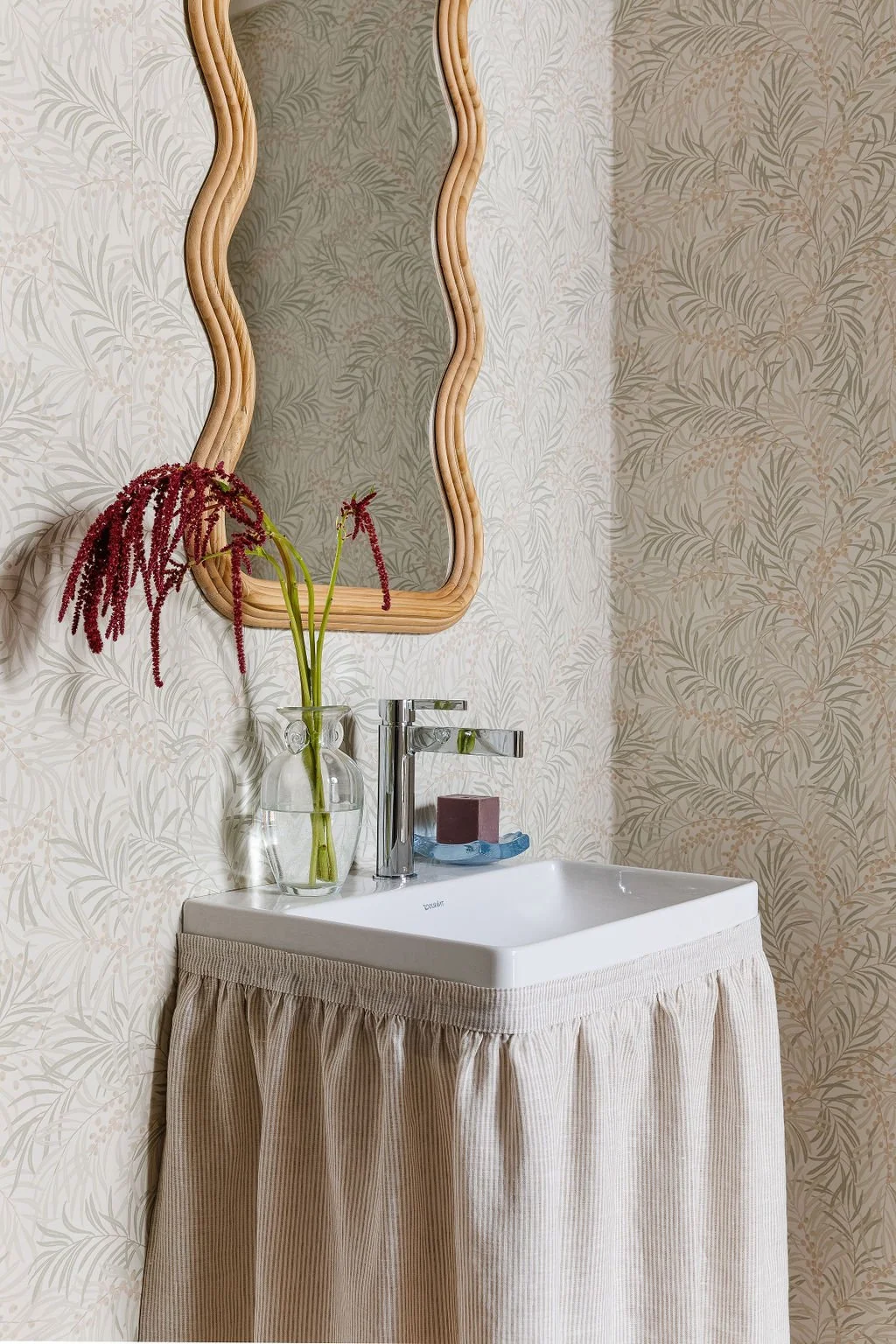 Washroom vanity with stiped fabric privacy skirt.