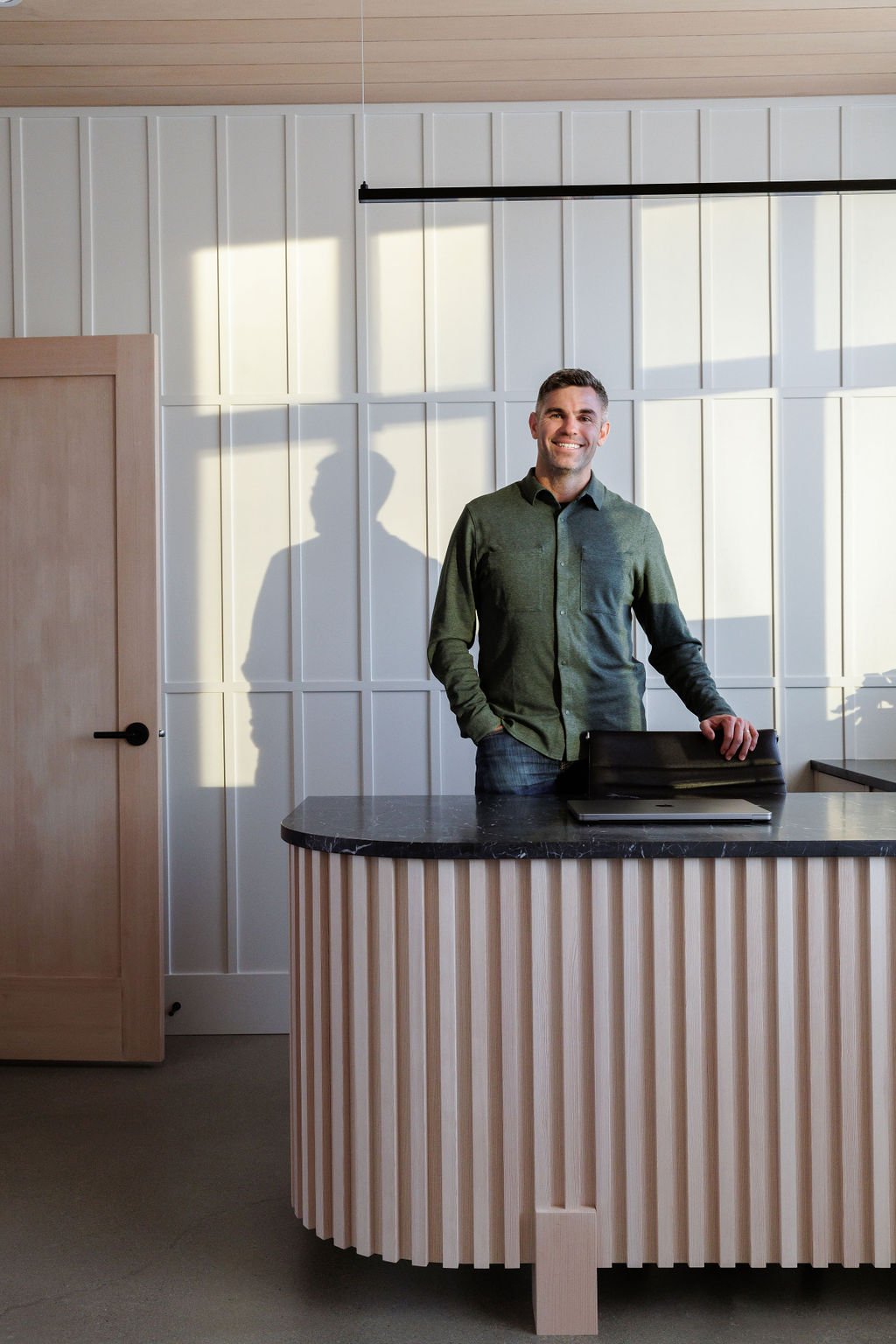 Photo of man standing behind custom office desk.