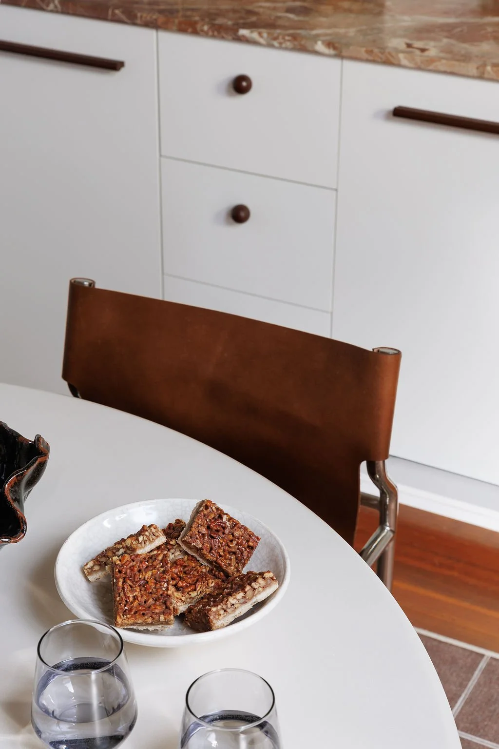 Round white table with pecan squares on plate and drinks. 