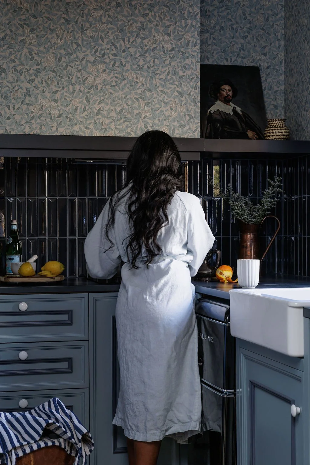 Selby Hotel owner Siya working in a robe in a moody blue kitchen.