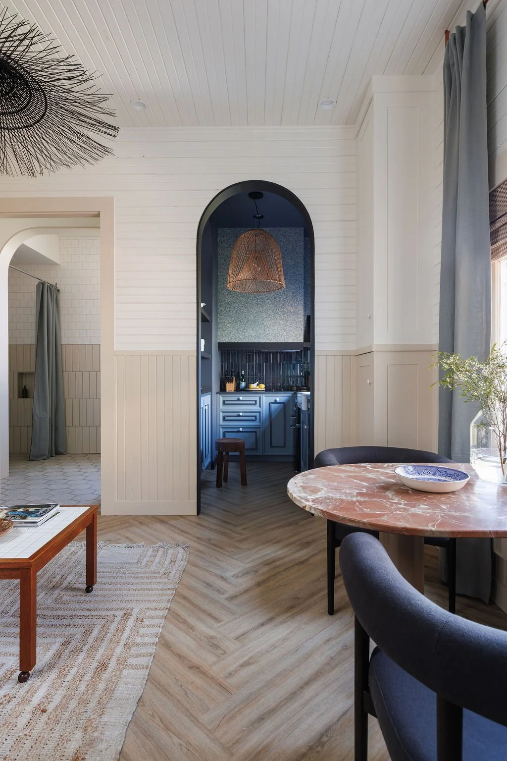 Arched doorway looking into kitchen with chairs and bistro table at Selby Hotel.
