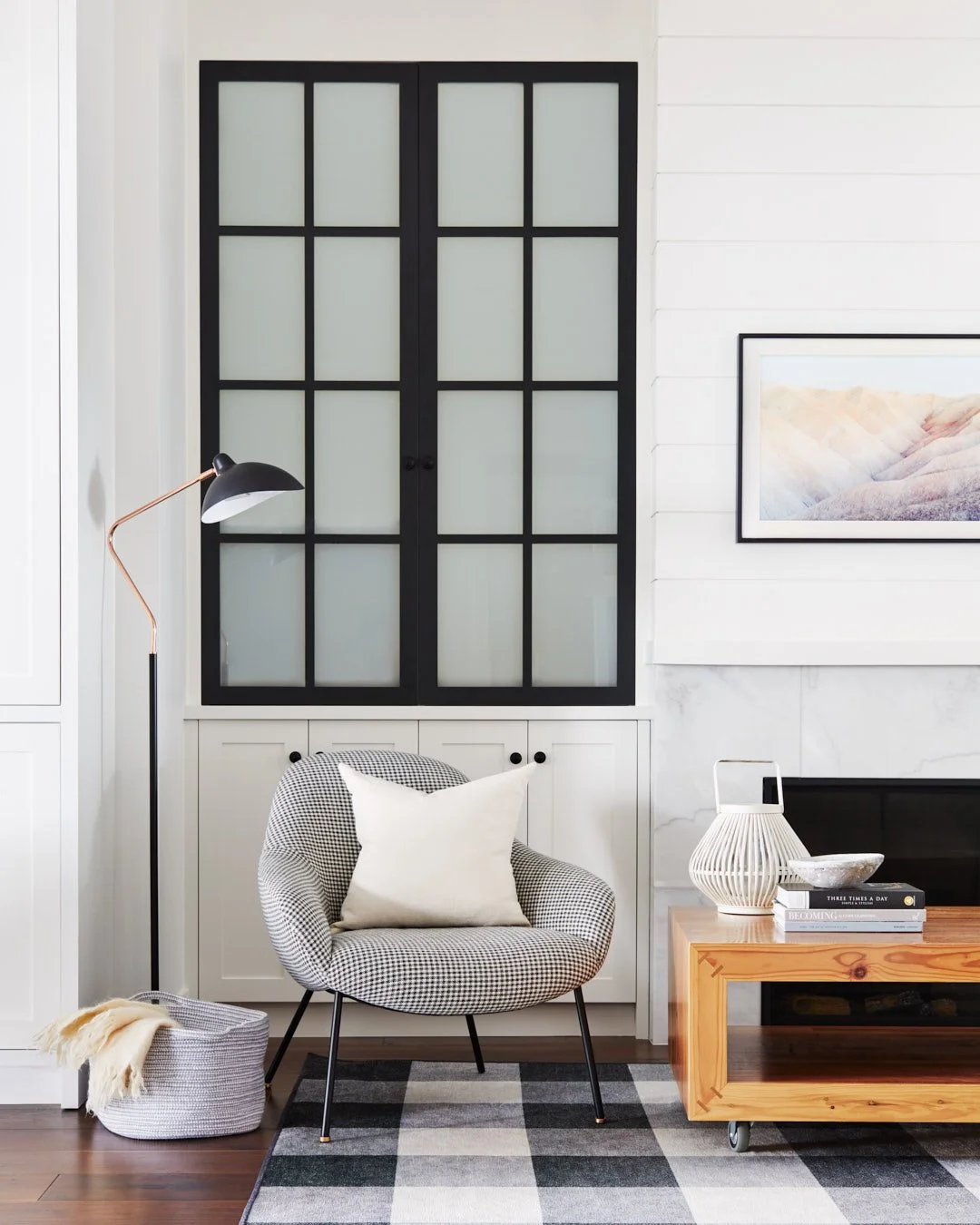 Close-up photo of side chair and coffee table in front of fireplace and white and black cabinetry.