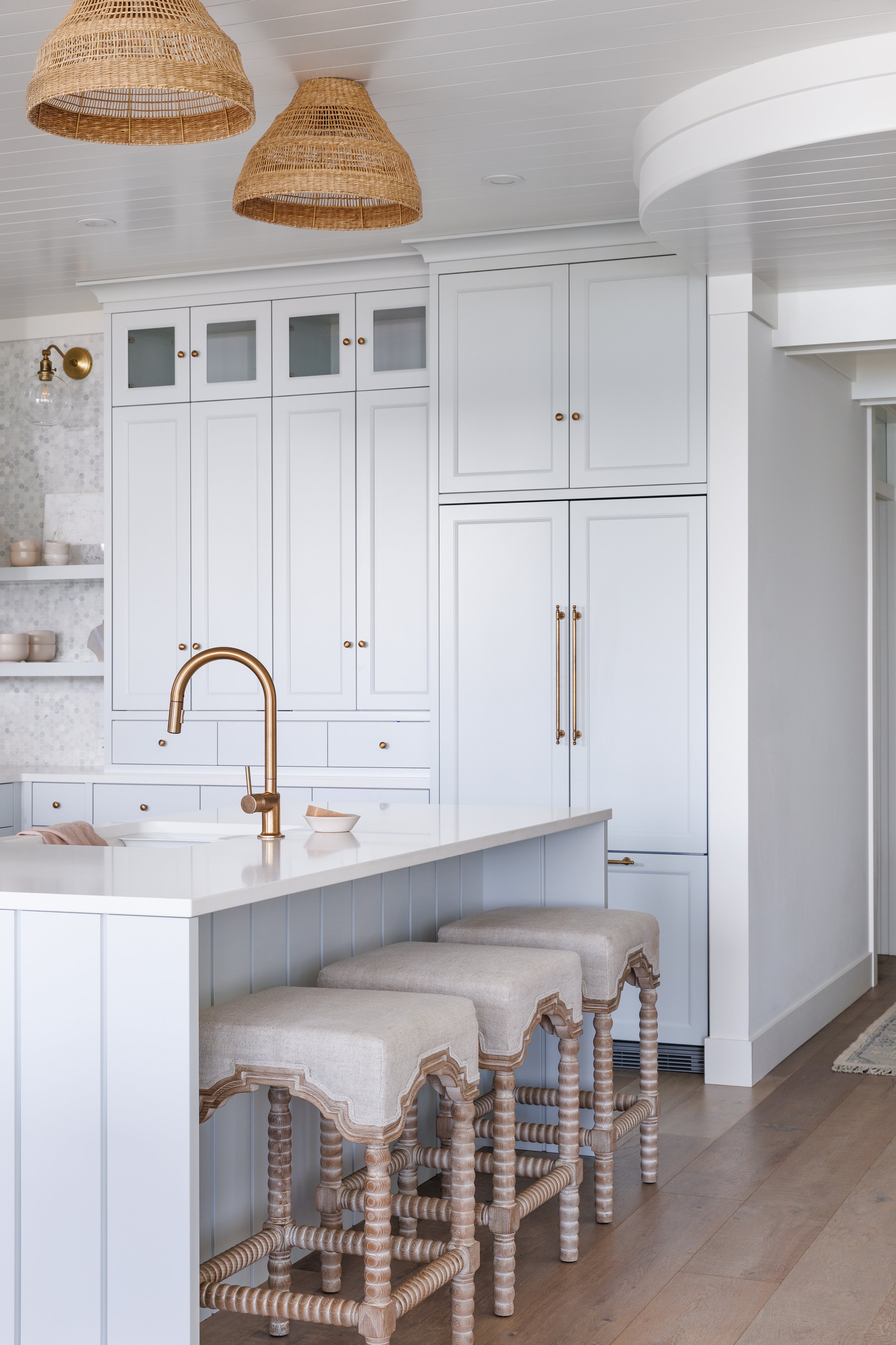 Beach house kitchen with wicker lighting and tall cabinetry.