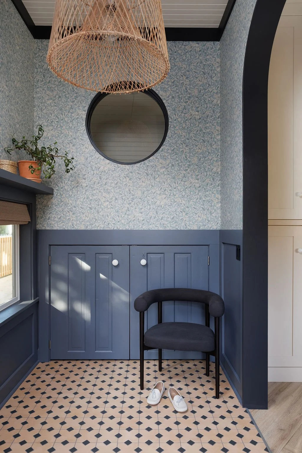 Livley entry with floral wallpaper comfortable side chair and round window.