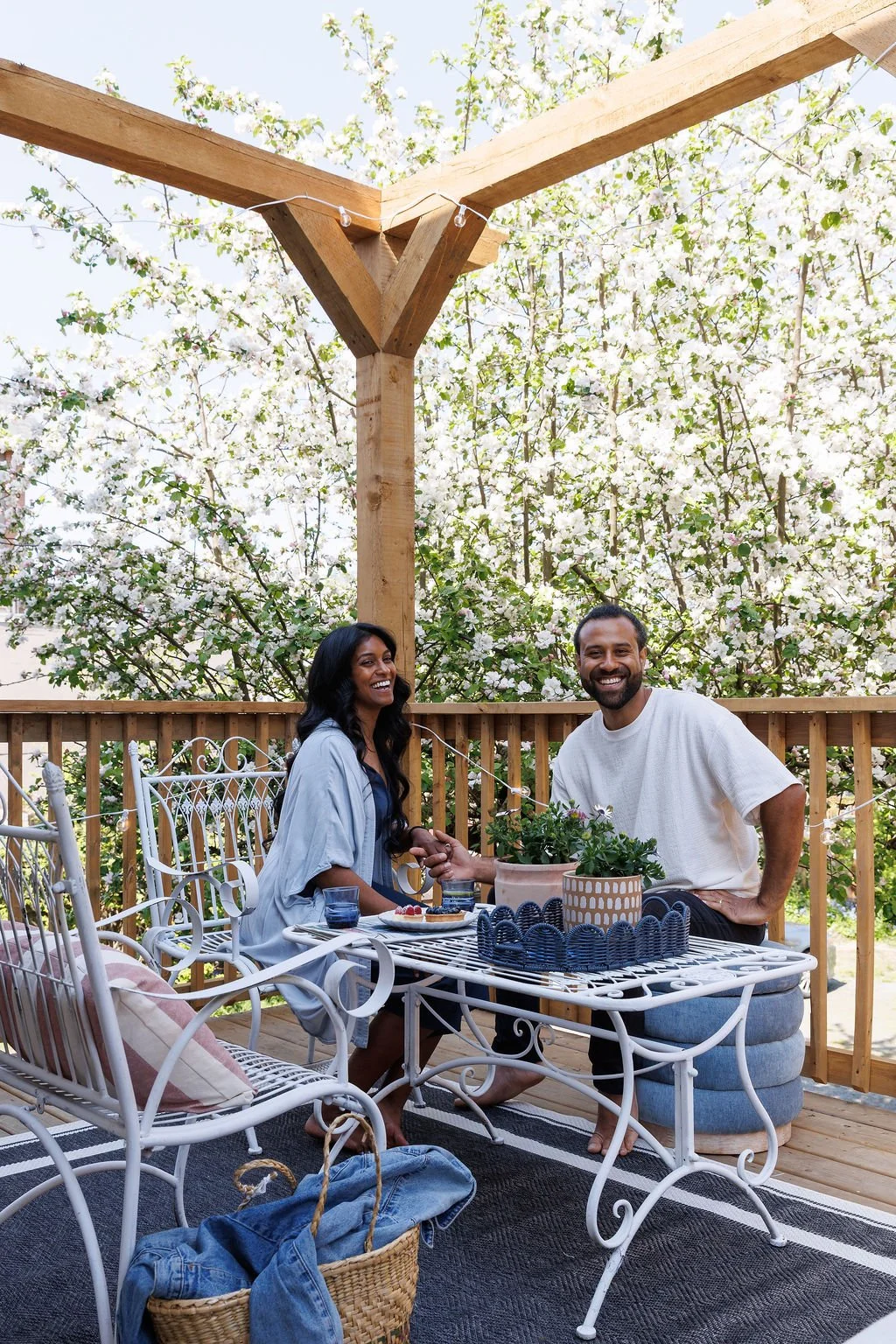 Siya and Rasila smiling sitting on the Selby Hotel back deck surrounded by apple tree blossoms, eating deserts on a sunny day.