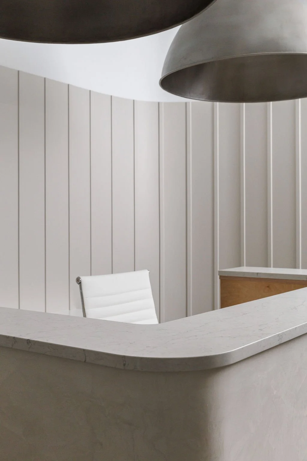 Close up photo of reception desk, large dome lighting and textural feature wall behind desk.
