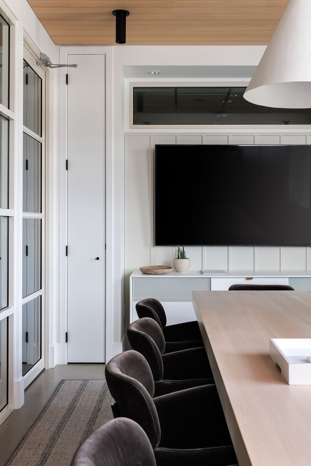 Close-up photo of boardroom with wood boardroom table, brown velvet chairs and TV.