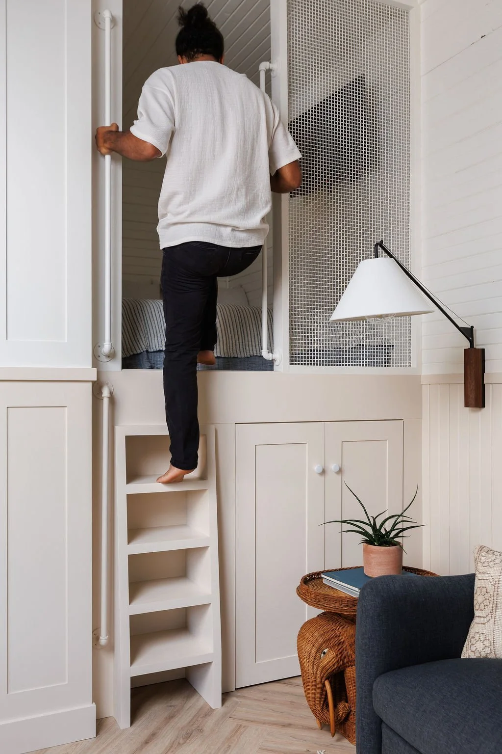 Man climbing up ladder to loft bed.