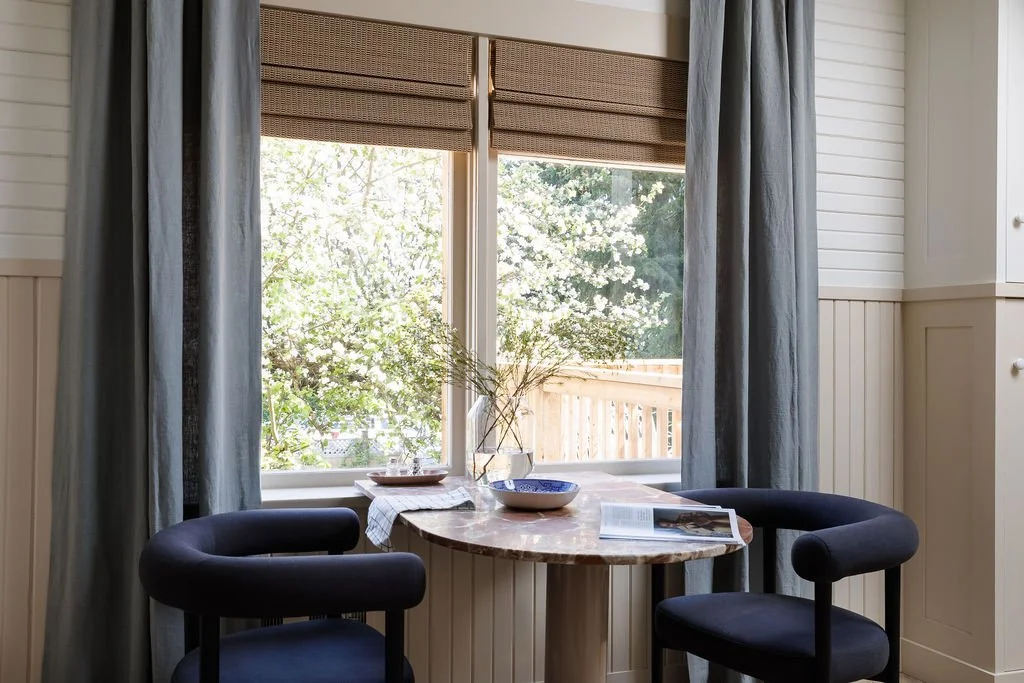 Two chairs at rounded marble bistro table in front of window looking out to apple tree.