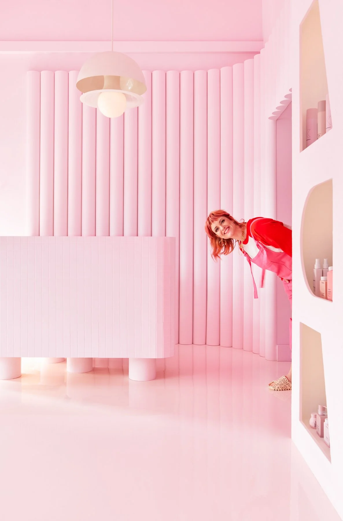 Pink Label salon owner Chantel Cody poses in a cute way through a doorway of her salon.