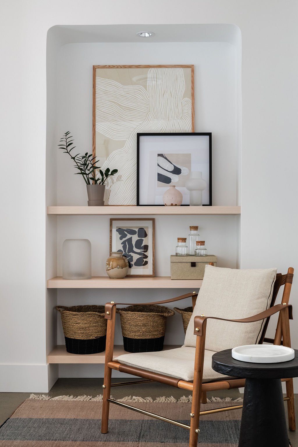 Photo of relaxed chair in front of floating shelving with shelving and decor.