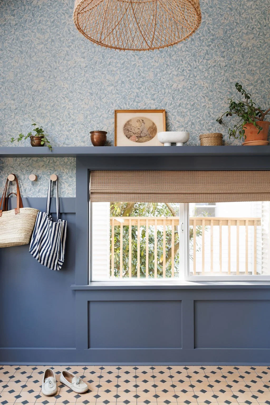 Entry with mosaic tile floor, floral wallpaper, window with seagrass blind.