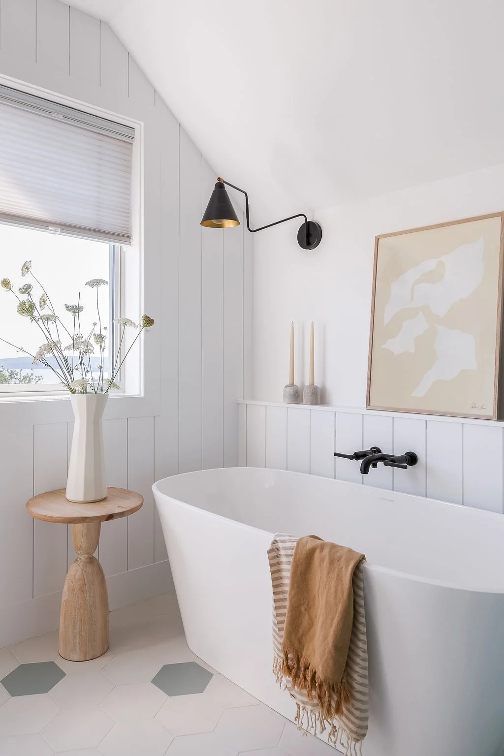 Soaker tub next to window surrounded by art and decor.