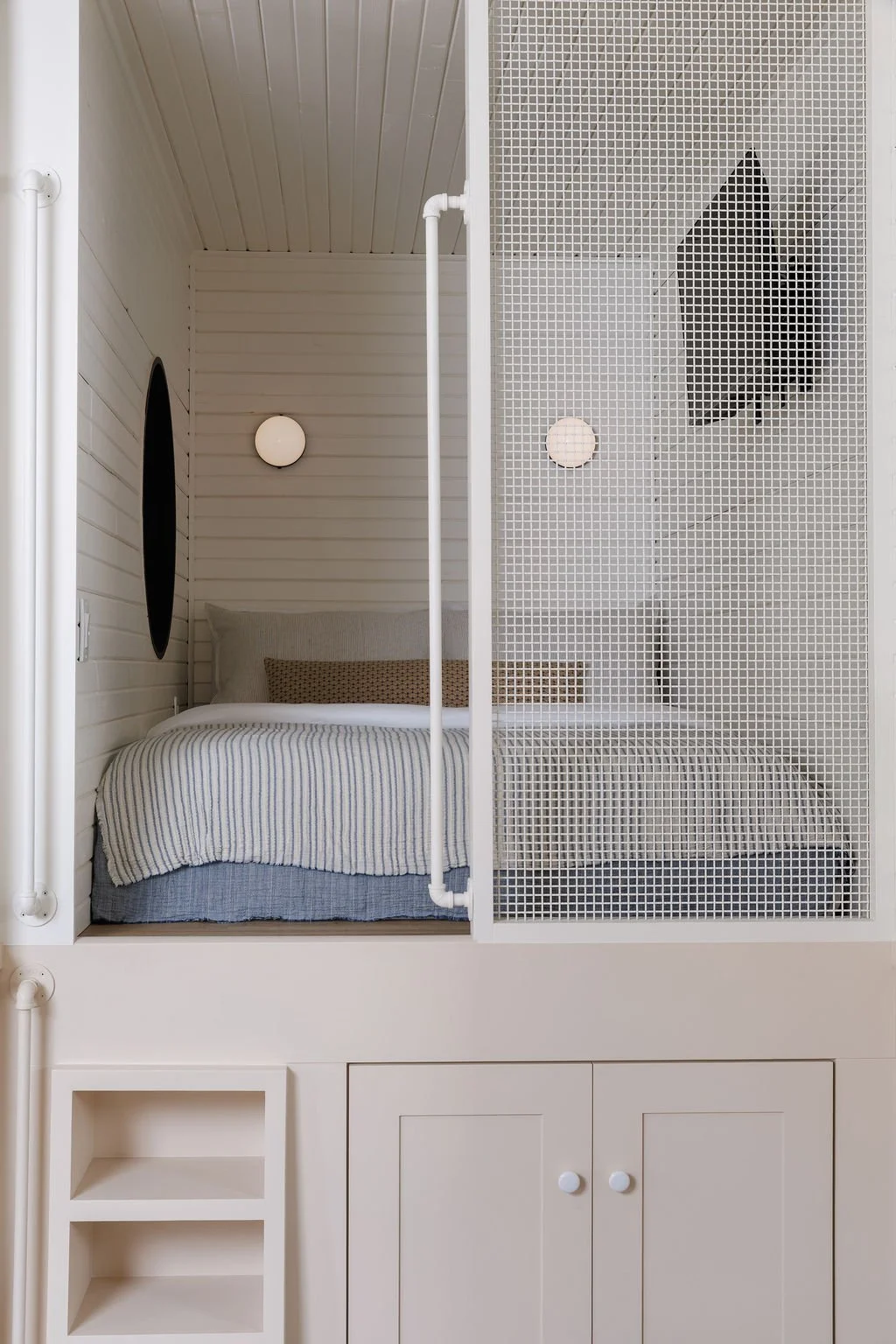 Loft bed with mesh privacy screen and wall mount lighting.