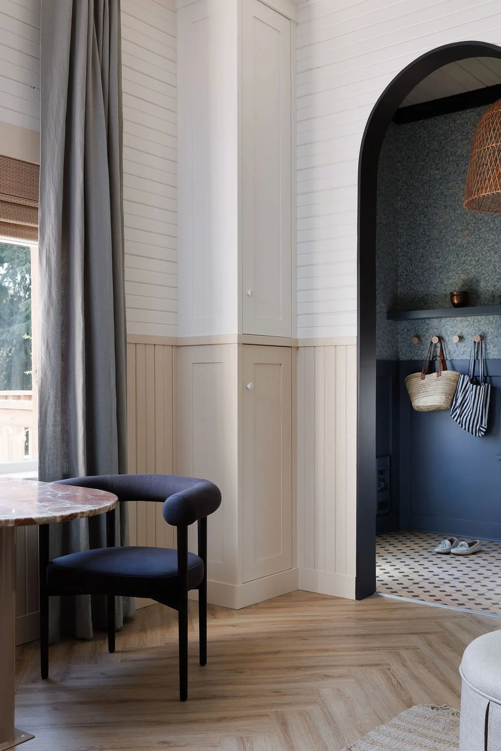 Bistro table with chair, arch looking through to entry with floral wall paper. 