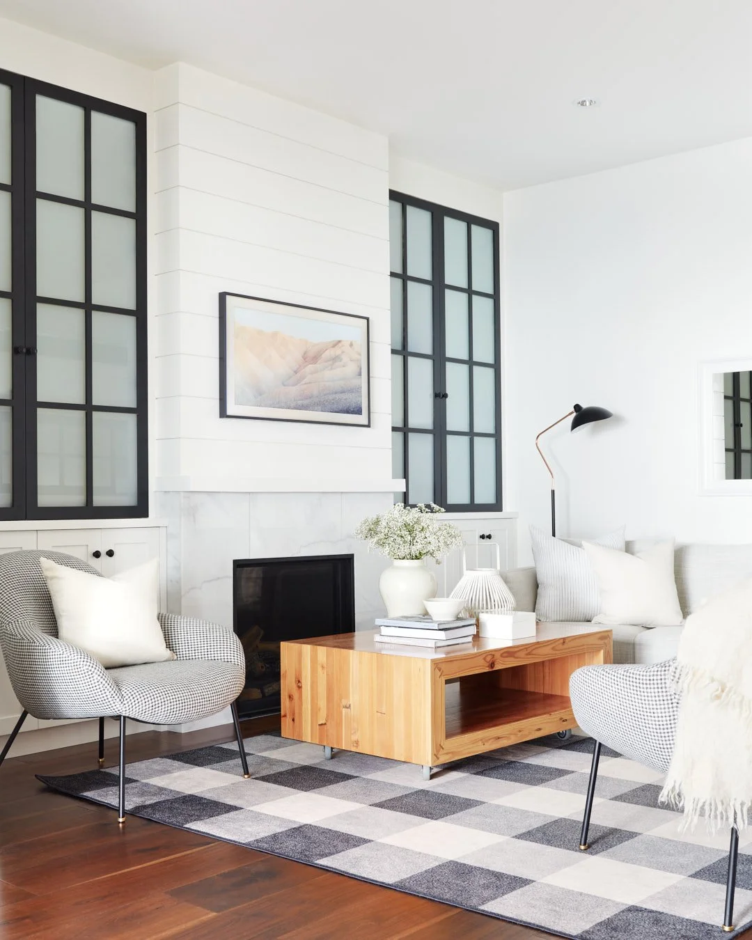 photo of cozy white living room with white and black furniture, fireplace and built-in cabinetry