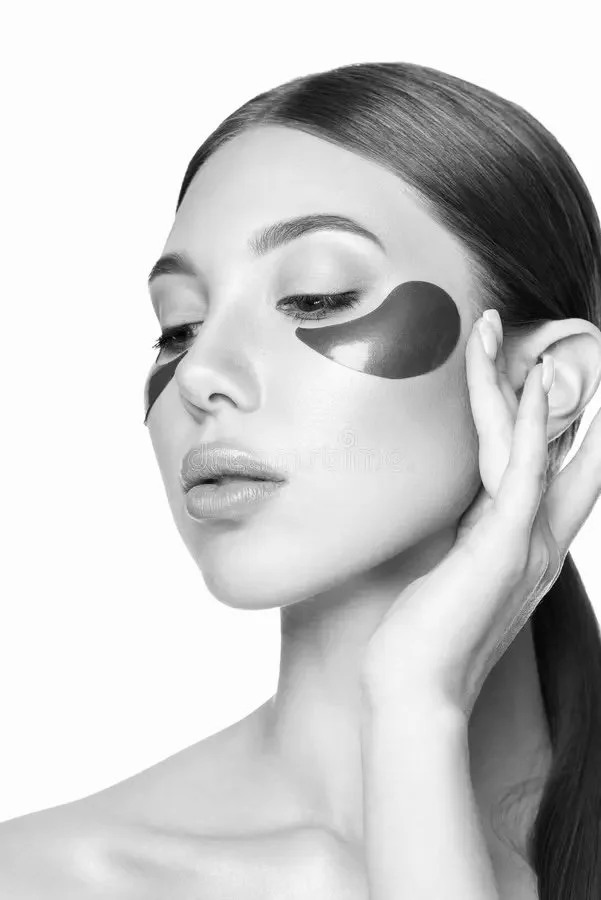 A woman applying under-eye patches for skincare.