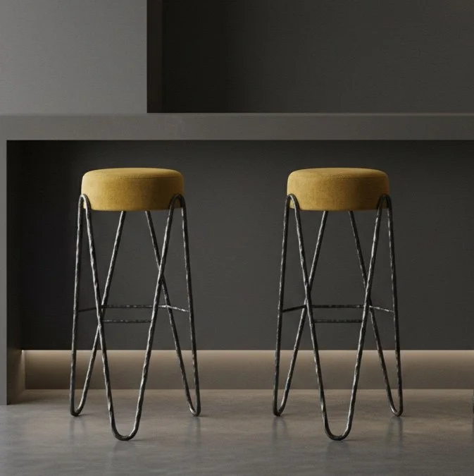 Set of Aranea forged steel stools in a modern interior. Custom metal finishes and upholstery options available for residential and hospitality projects.