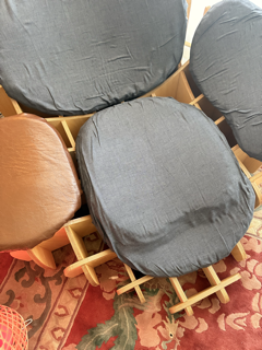 Set of cushioned chairs with wooden frames, one with a black cushion, others with gray and brown cushions, on a patterned rug.