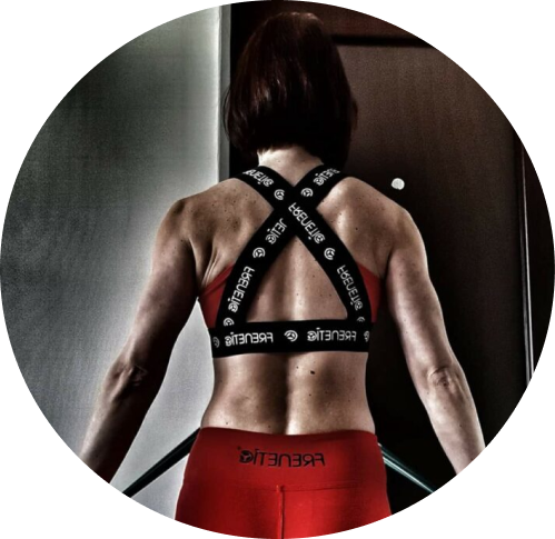 Rear view of a woman with short dark hair in athletic clothing, standing in a gym or fitness center.